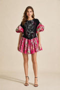 Front view of model wearing black graphic print puff sleeve drop waist mini dress