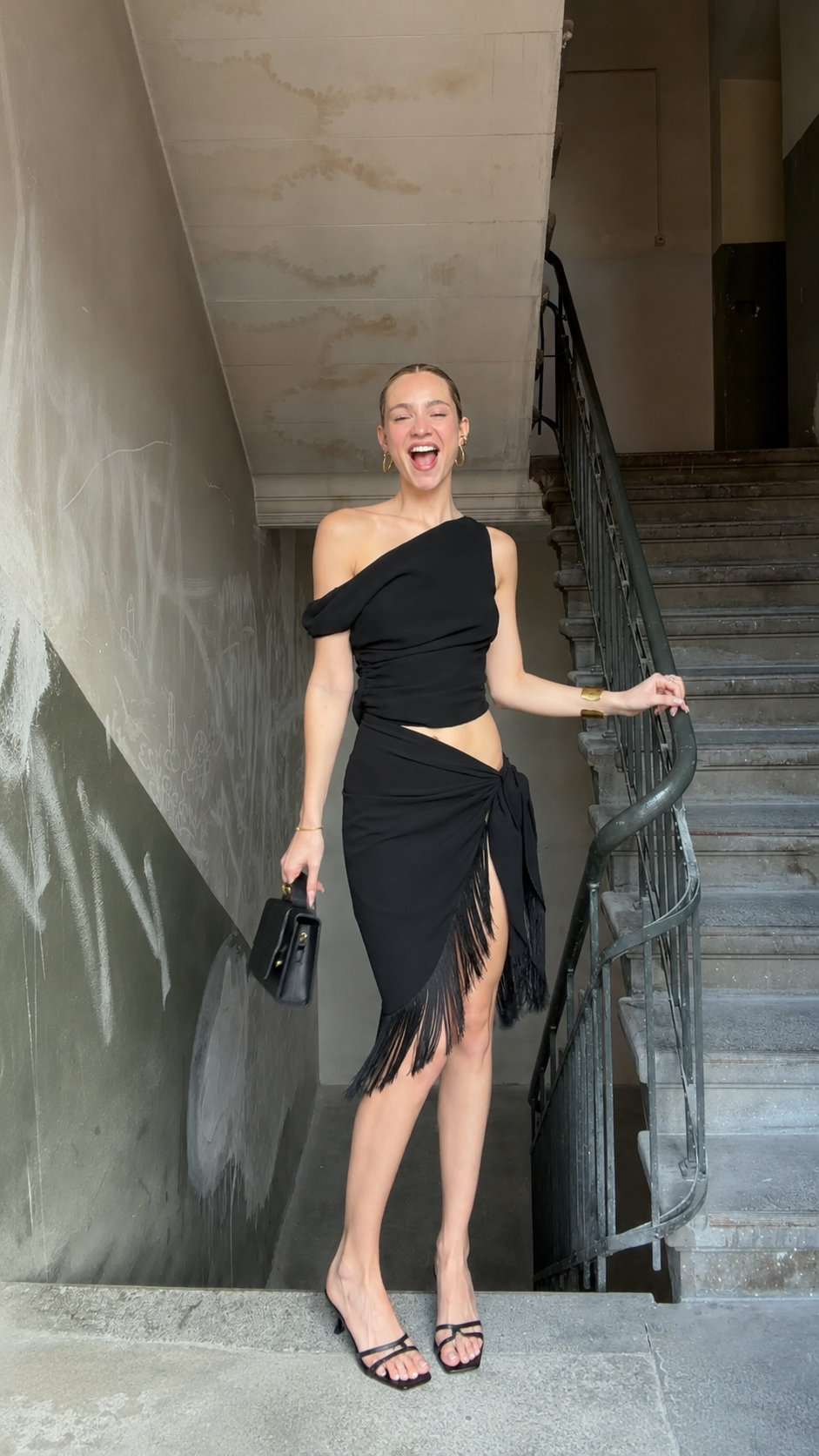 Front view of black one shoulder fringe cutout midi dress with slit