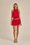 Model wearing red halter top and ruffled mini skirt set from the front