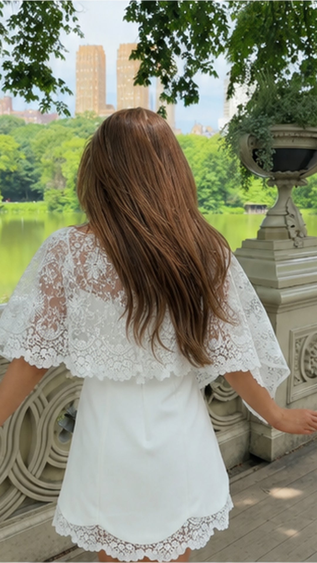 Back view of white lace overlay mini dress with sheer floral cape sleeves