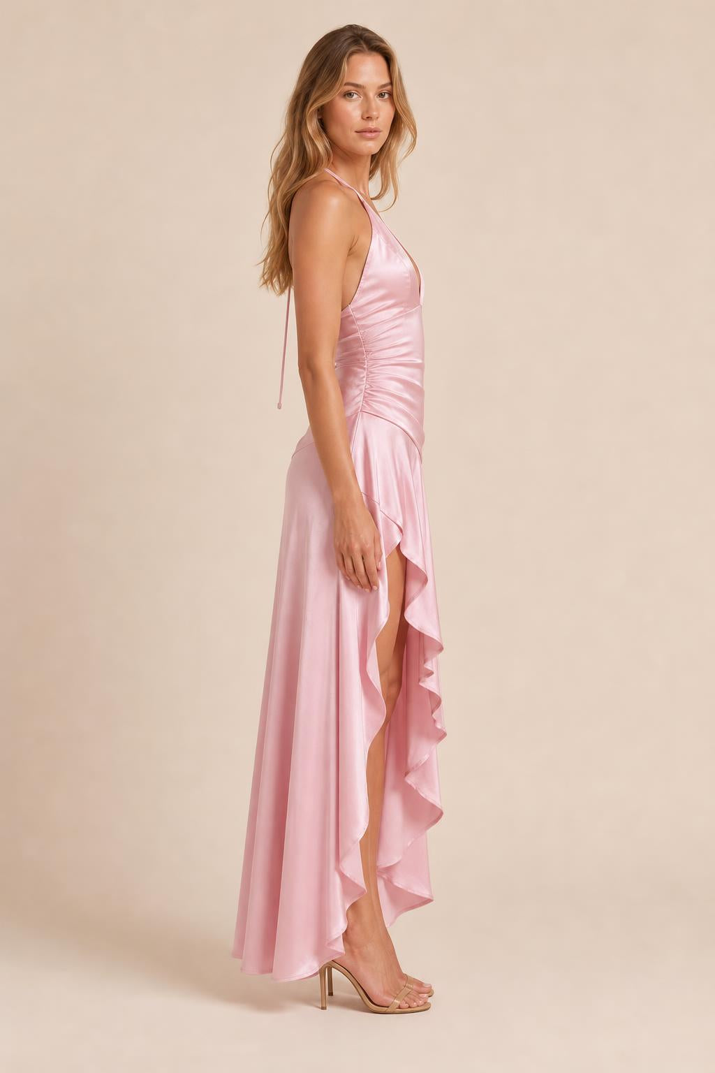Model wearing pink satin halter dress showing side profile and high-low hem
