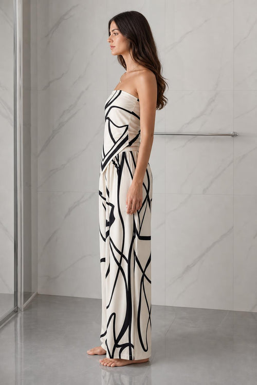 Side profile view of woman wearing beige and black abstract print strapless jumpsuit