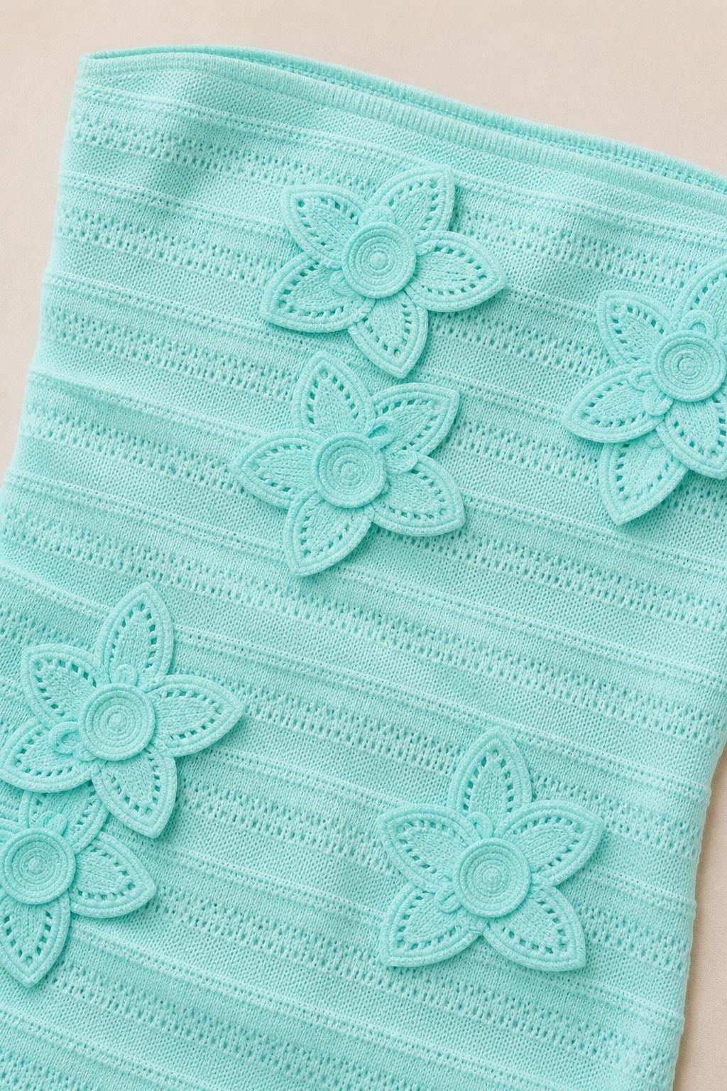 Close-up detail of textured knit fabric and 3D floral appliques