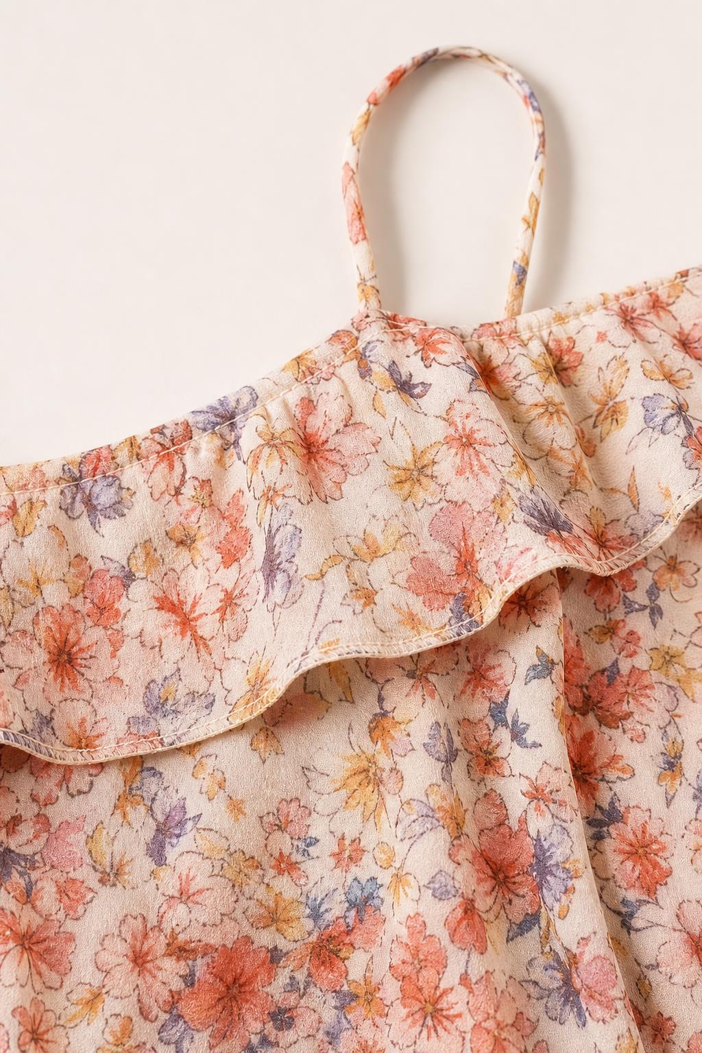 Close-up detail of ruffle neckline and spaghetti strap