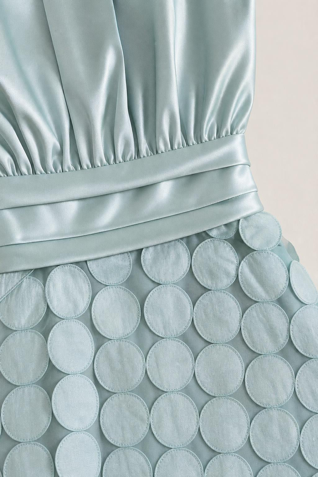 Close-up detail of satin bodice and circle textured skirt overlay