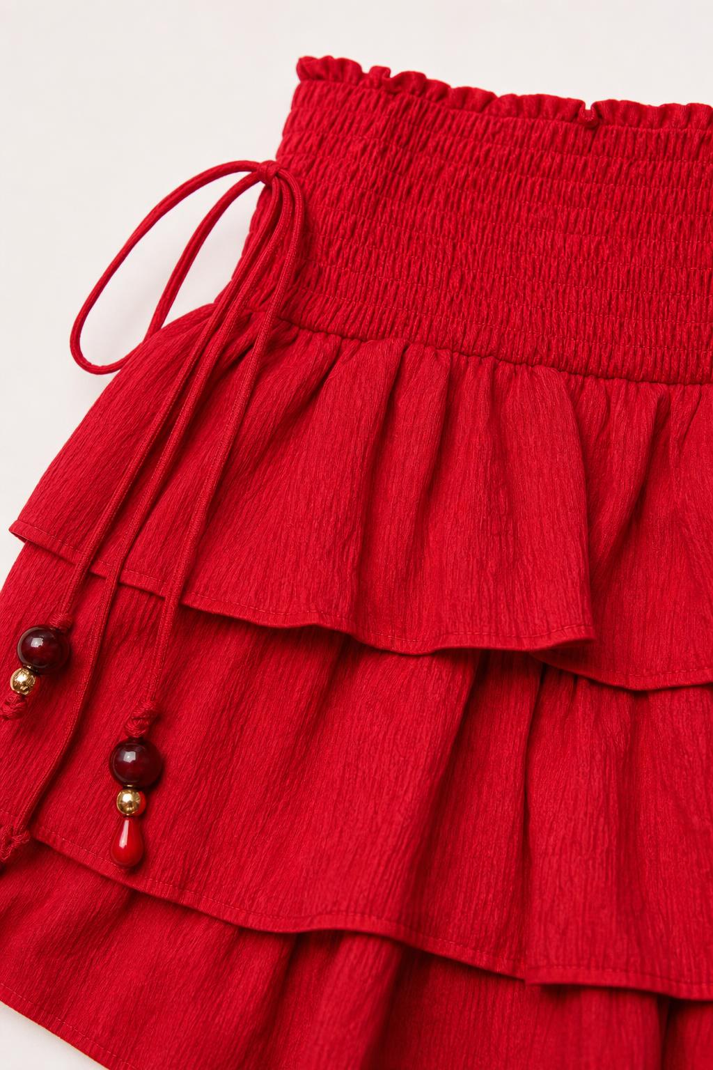 Close-up detail of red skirt smocked waistband and beaded drawstring