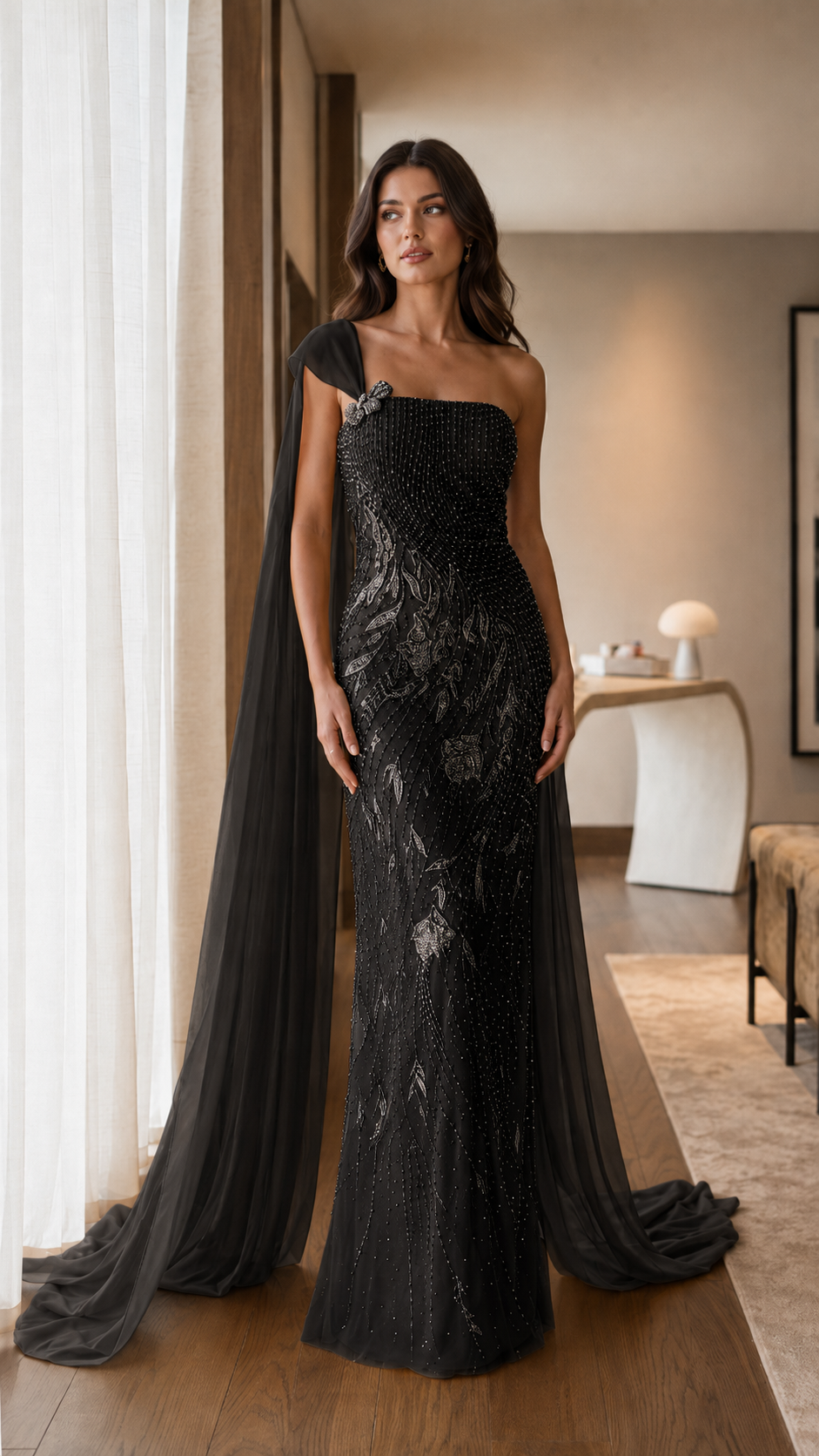 Front view of black one-shoulder embellished mermaid evening gown with cape