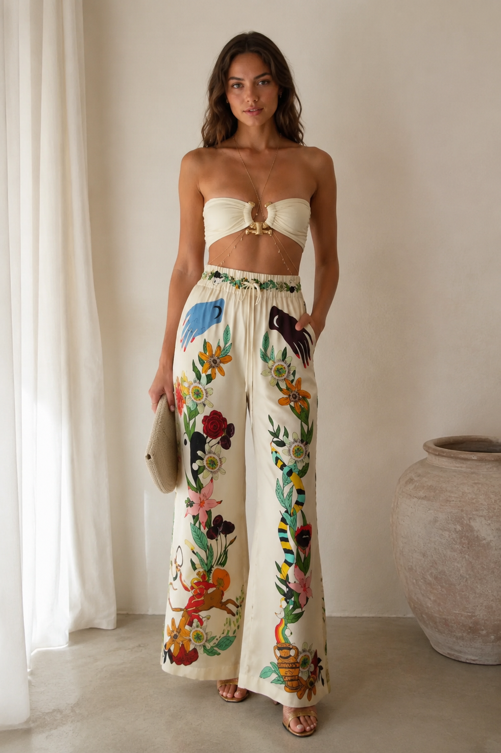Front view of ivory bandeau top and ivory floral wide-leg pants set with clutch