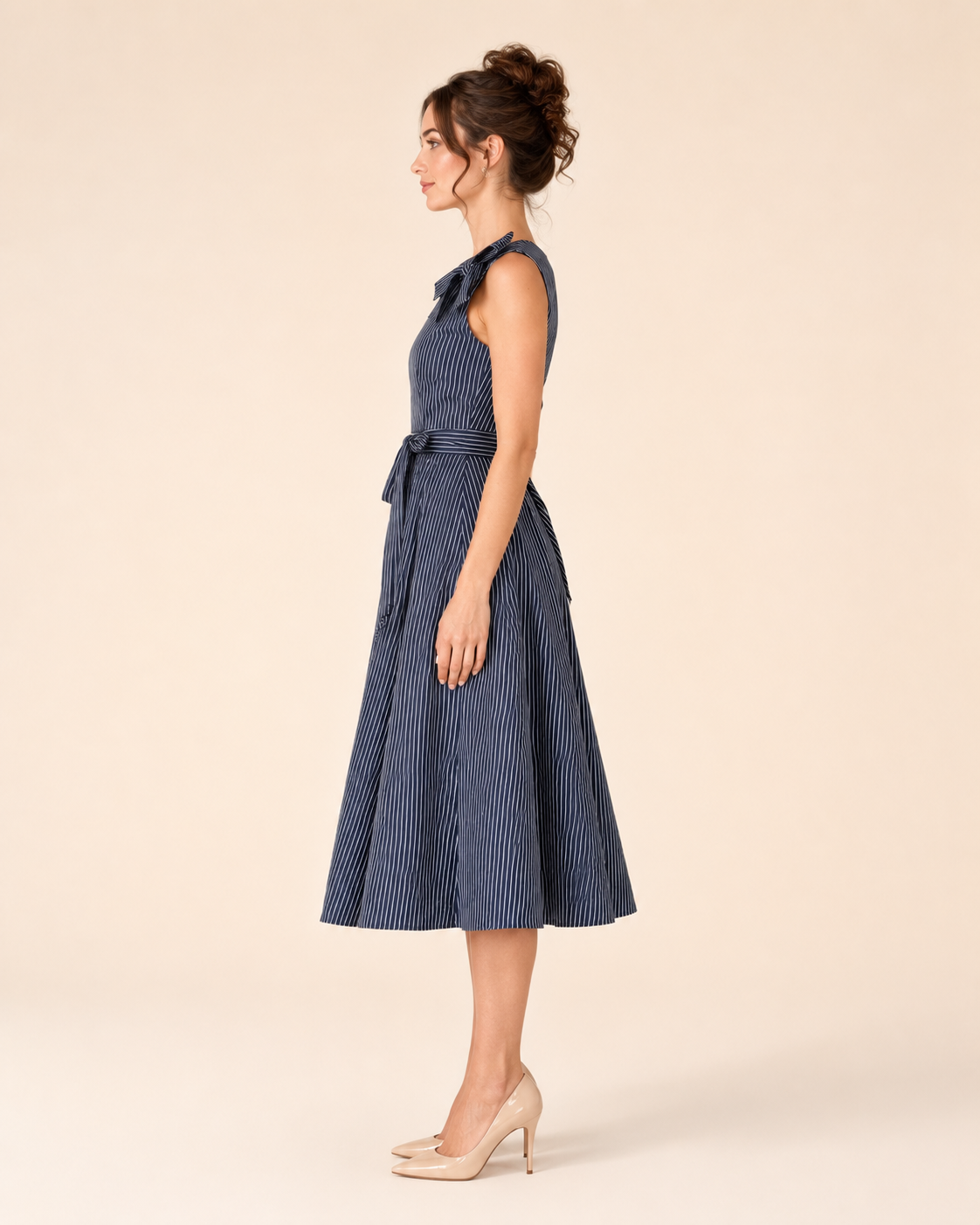 Side view of navy sleeveless striped midi dress showing shoulder bow and flared shape