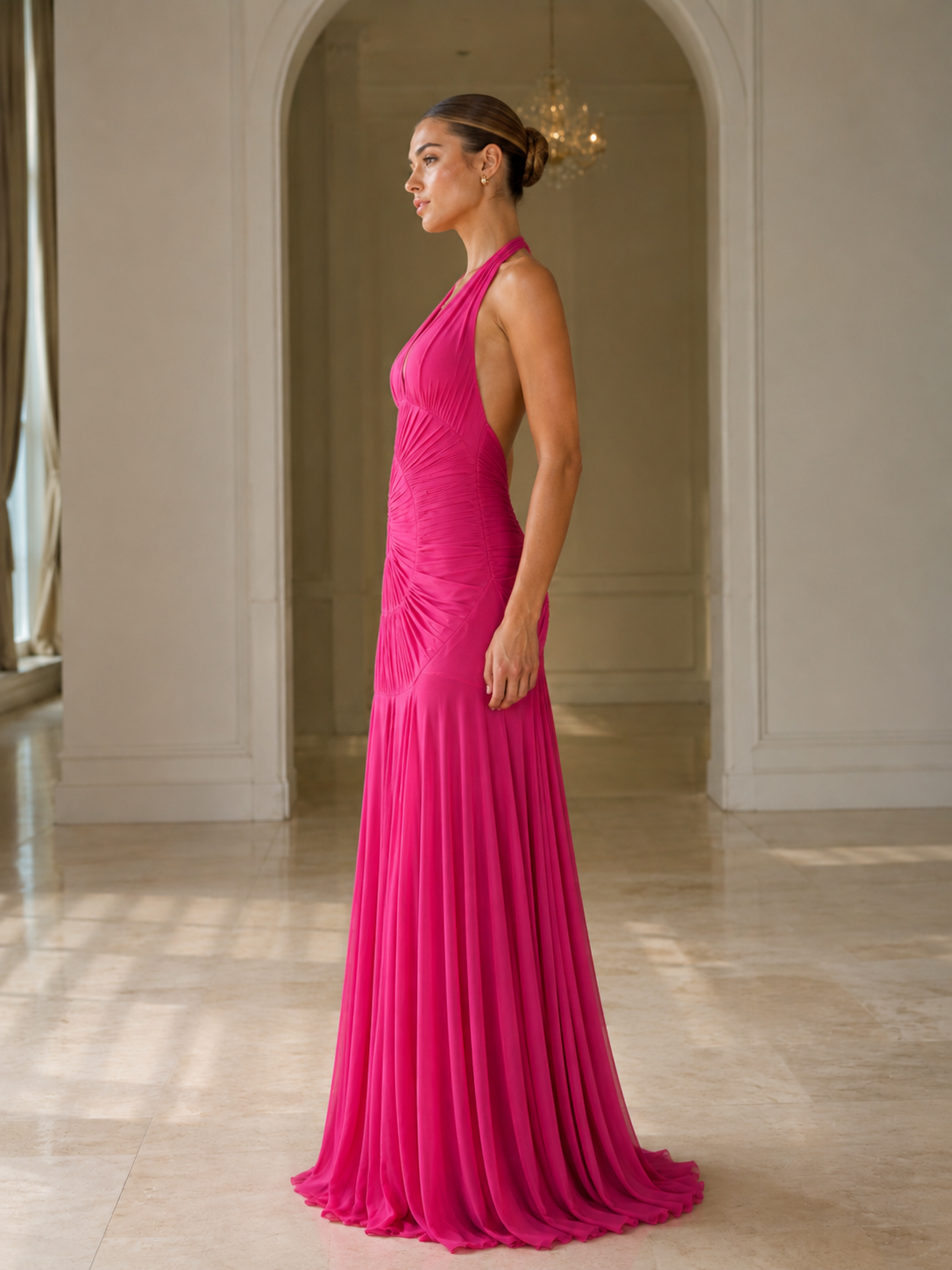 Side view of hot pink halter mermaid gown with floor-length drape