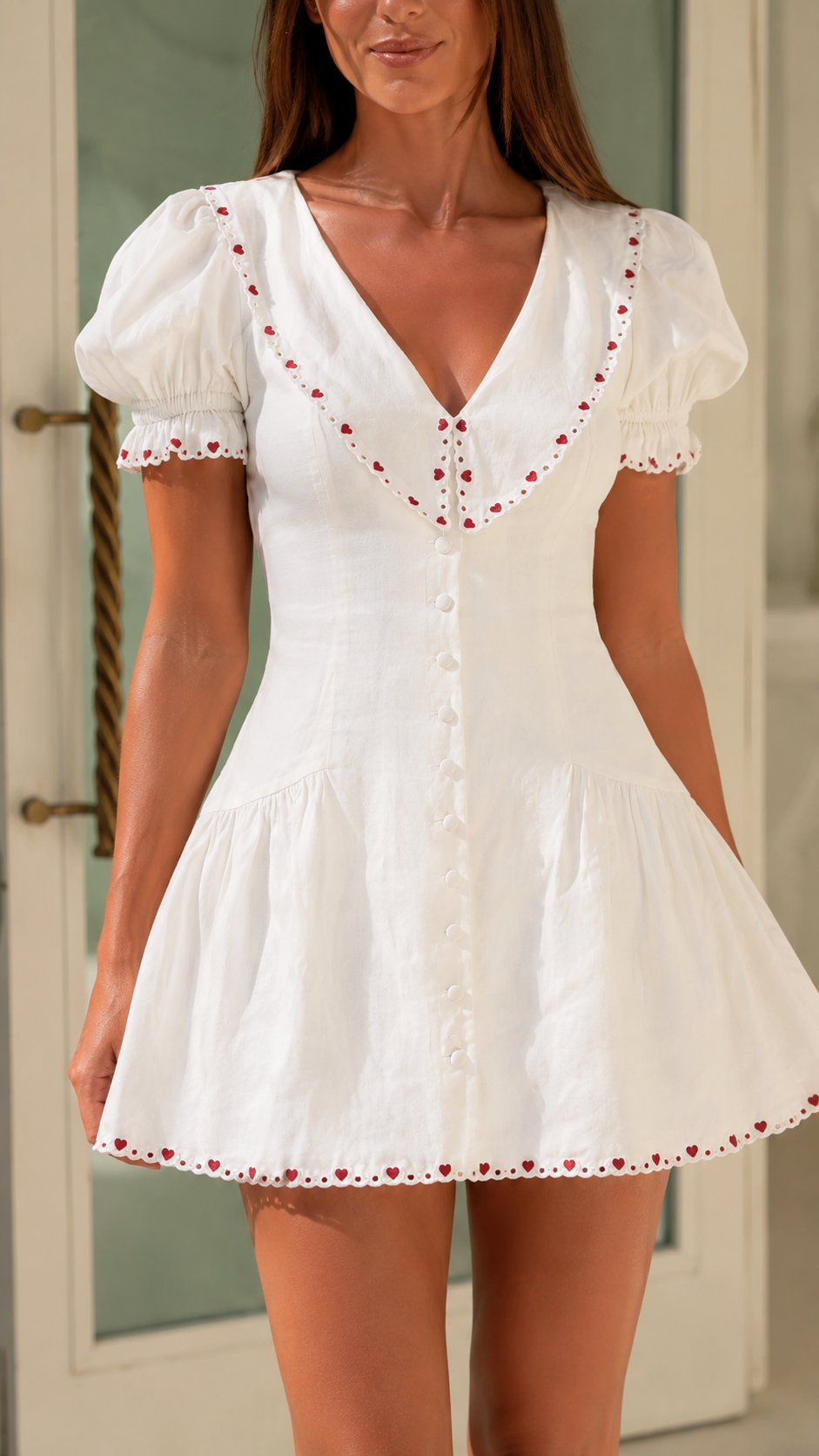 Close-up of white dress showing V-neck collar, front buttons, and embroidered trim