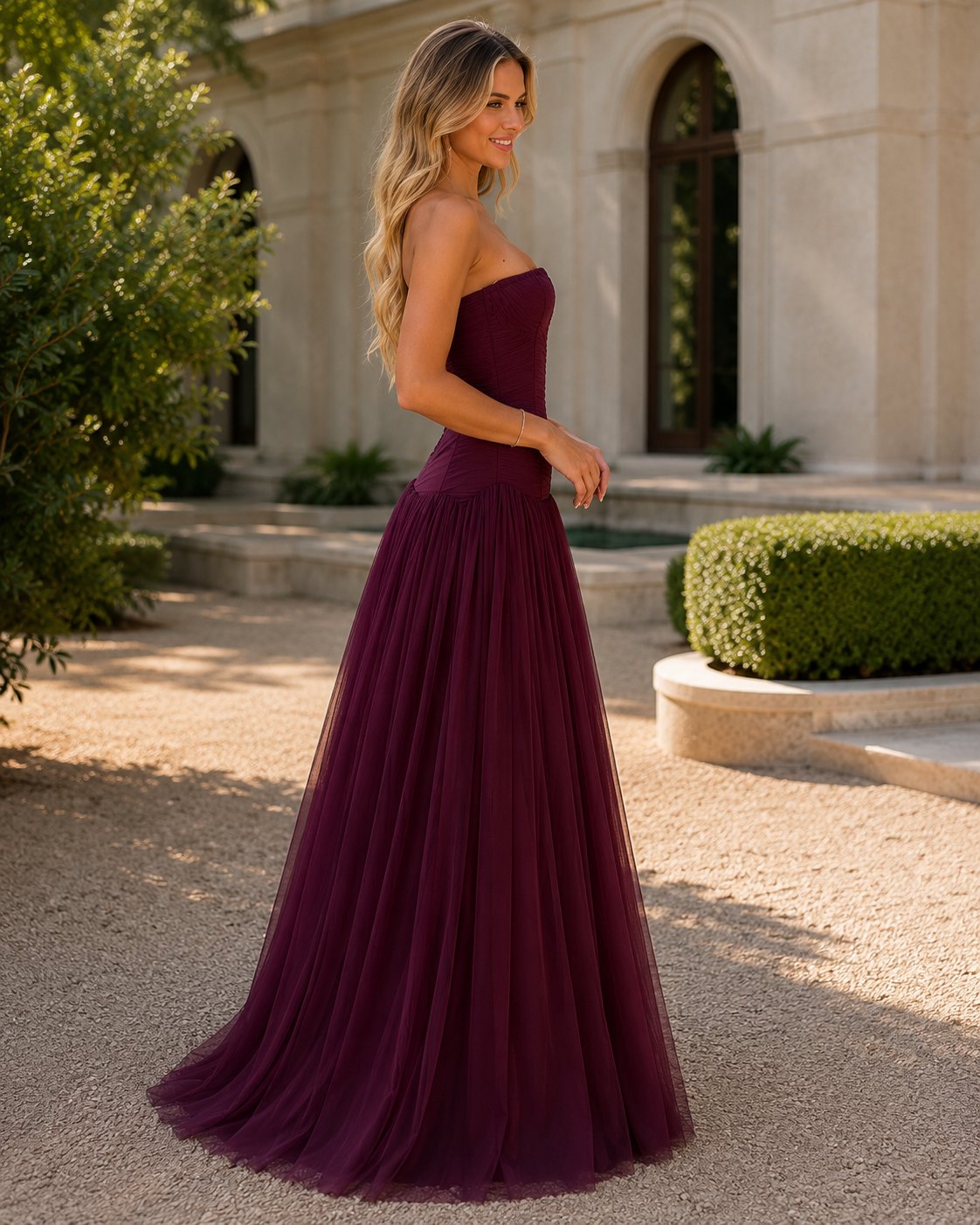 Side view of burgundy strapless floor-length gown with fitted bodice and soft volume